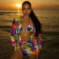 Woman in a colorful swimsuit standing on a beach at sunset
