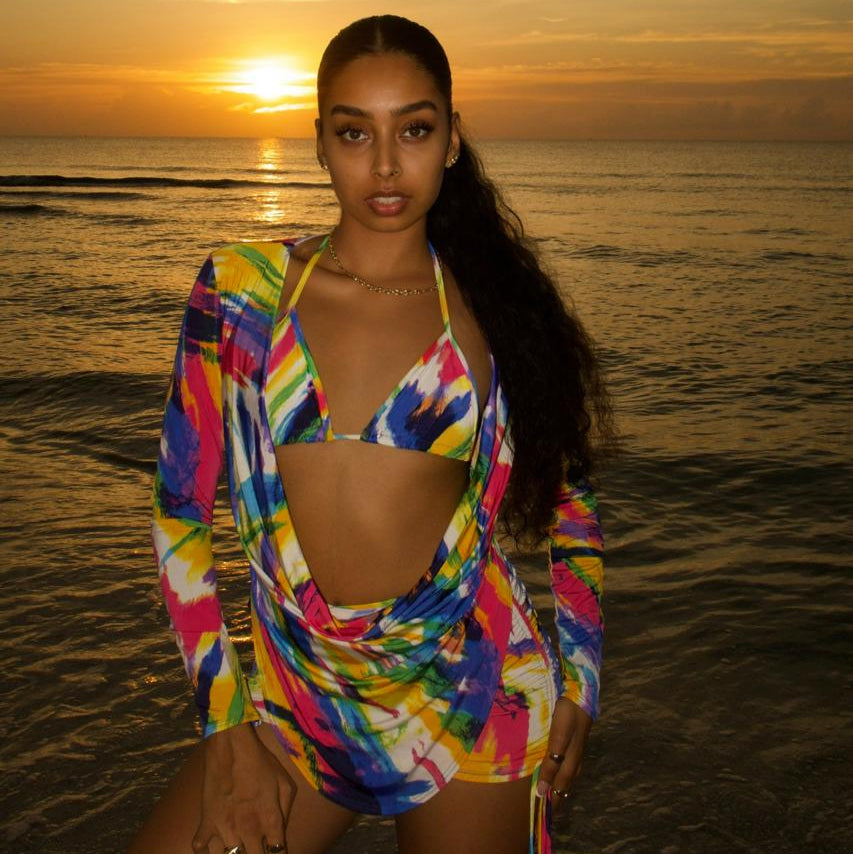 Woman in a colorful swimsuit standing on a beach at sunset